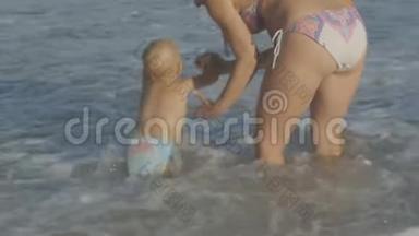 <strong>年轻</strong>的白种人<strong>母亲</strong>和两岁的金发碧眼的婴儿一起玩，享受着海浪的飞溅，泡沫<strong>牵</strong>手在海上